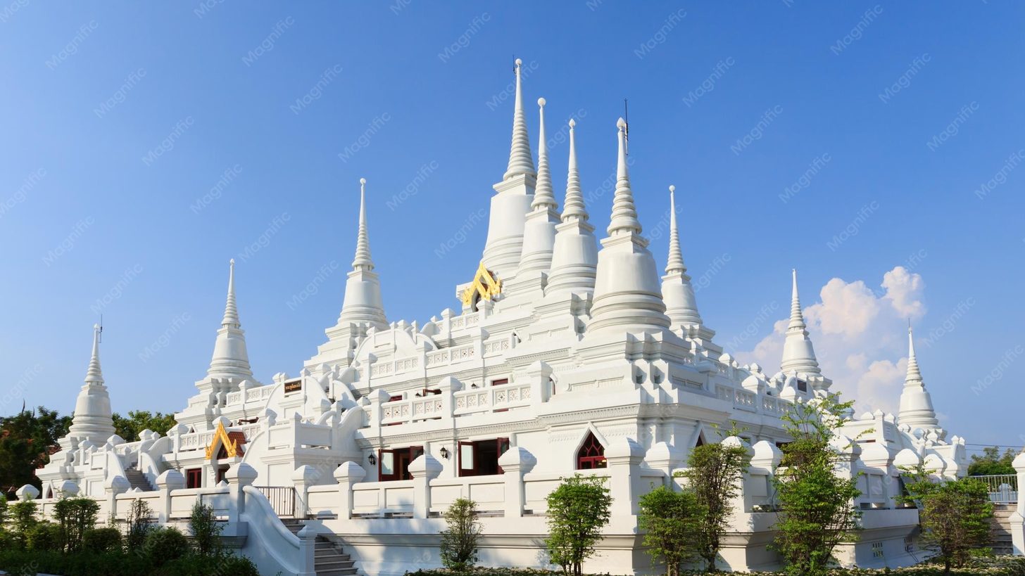 A white temple with many spires under a blue sky in Samut Prakan province