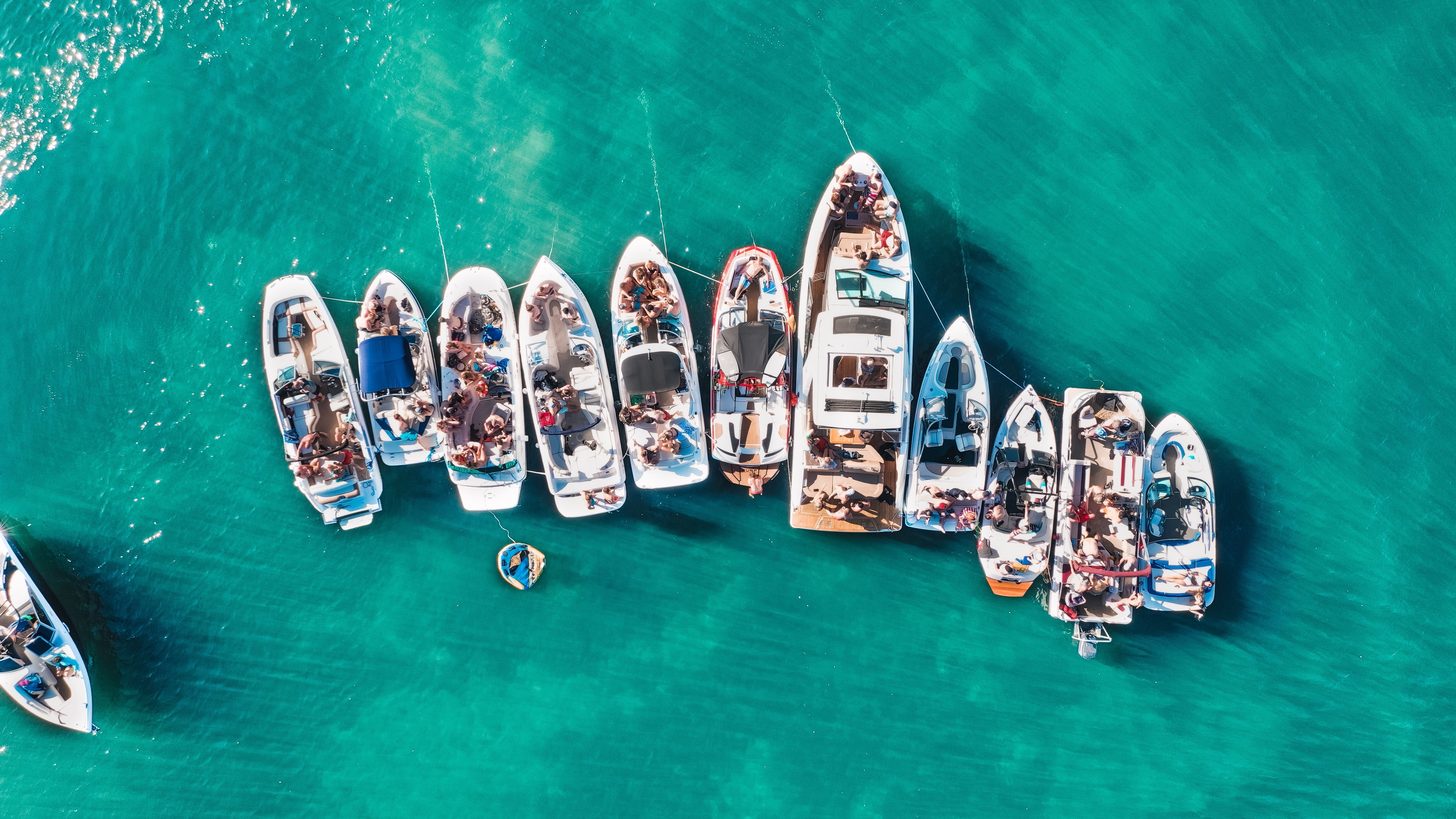 Speedboats moored side by side in clear turquoise water, seen from above
