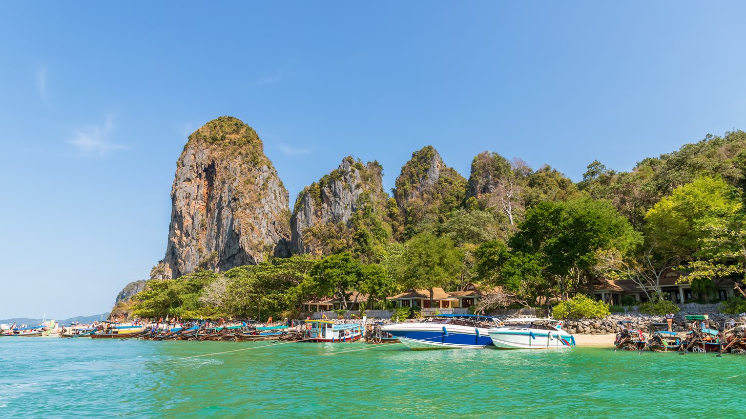 Eau turquoise limpide et bateaux amarrés au pied de falaises calcaires à Ao Phra Nang, près de Railay, à Krabi