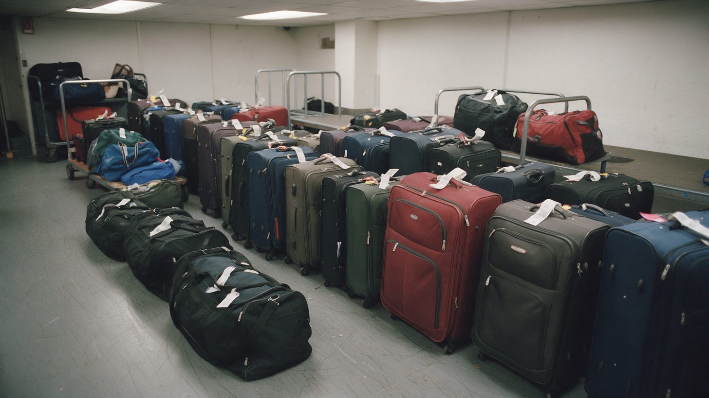 Des rangées de valises et de sacs étiquetés attendent au sol dans une salle de stockage de bagages