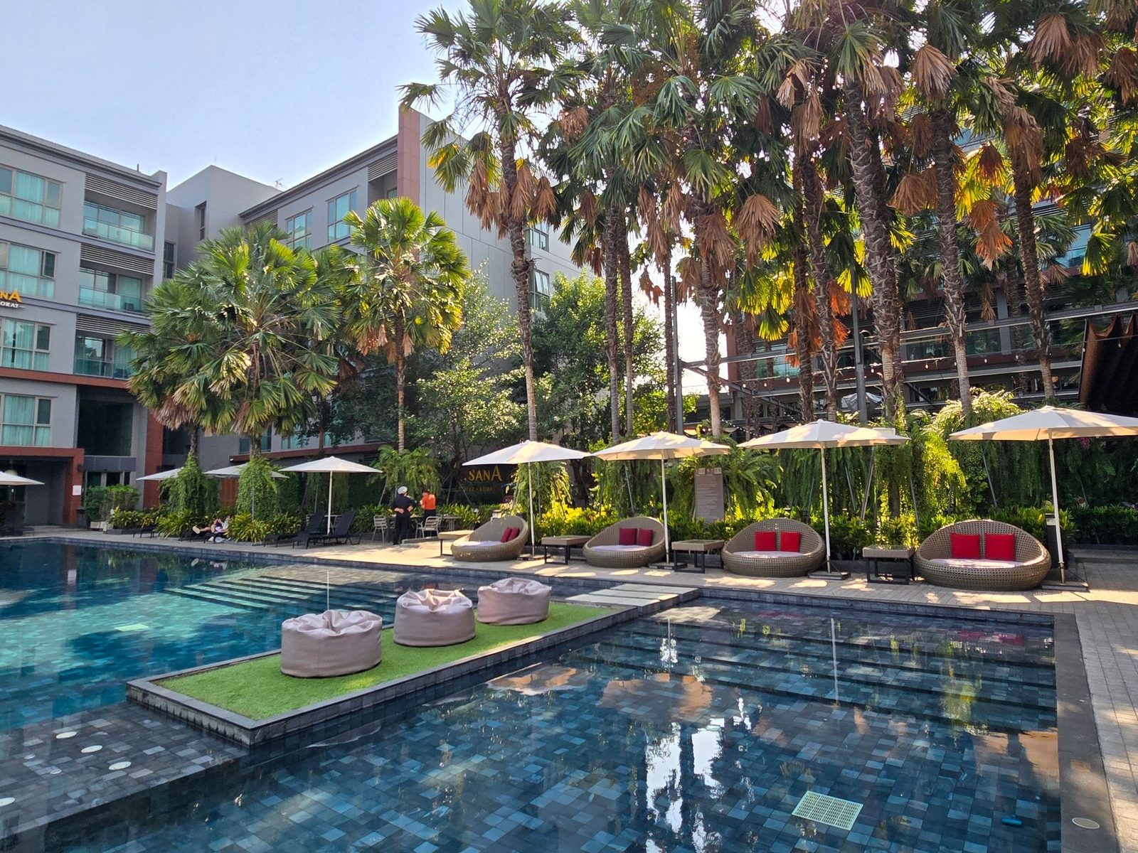 Saltwater swimming pool with loungers and palms at AISANA Hotel Korat