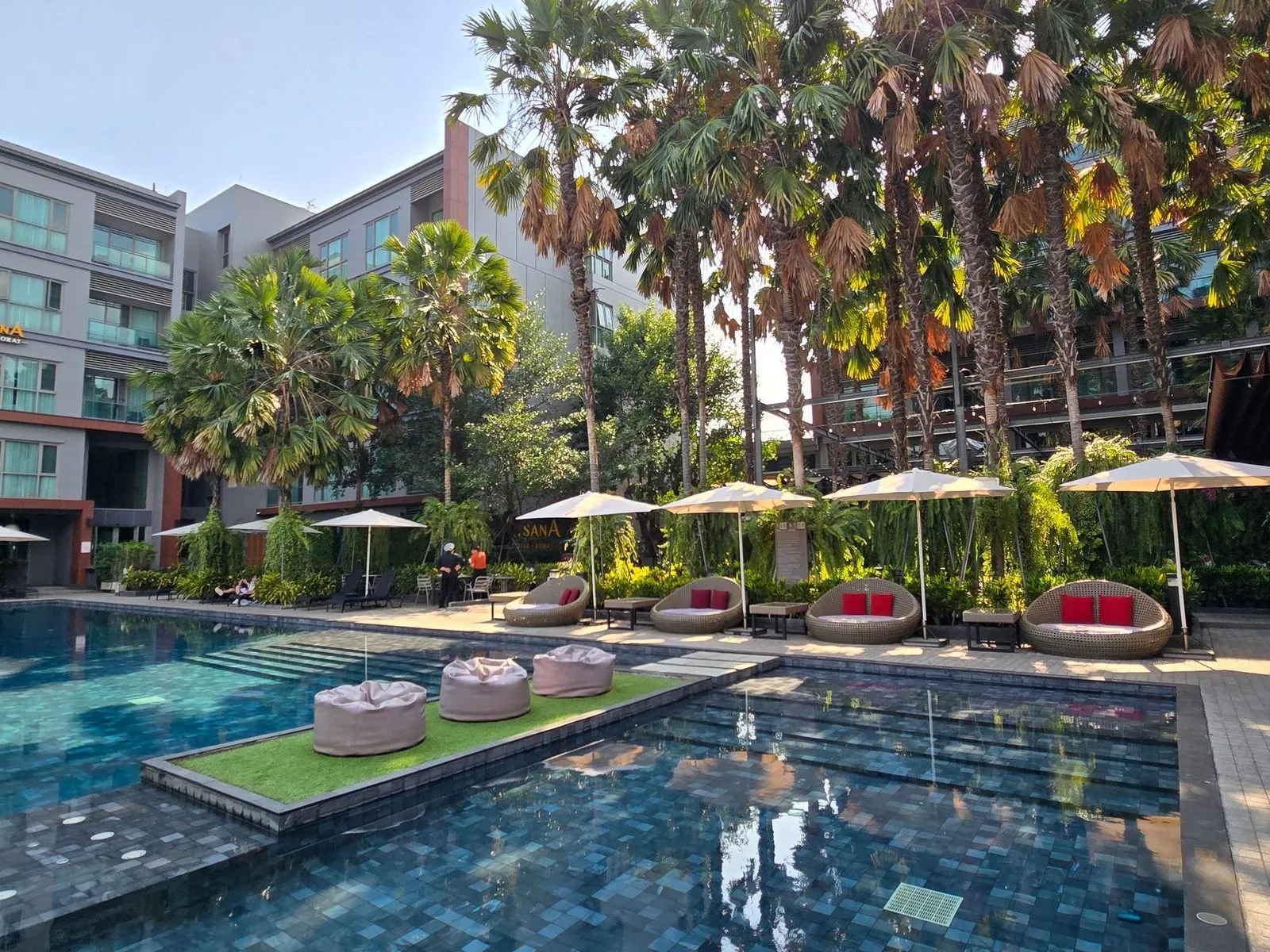Saltwater swimming pool with loungers and palms at AISANA Hotel Korat