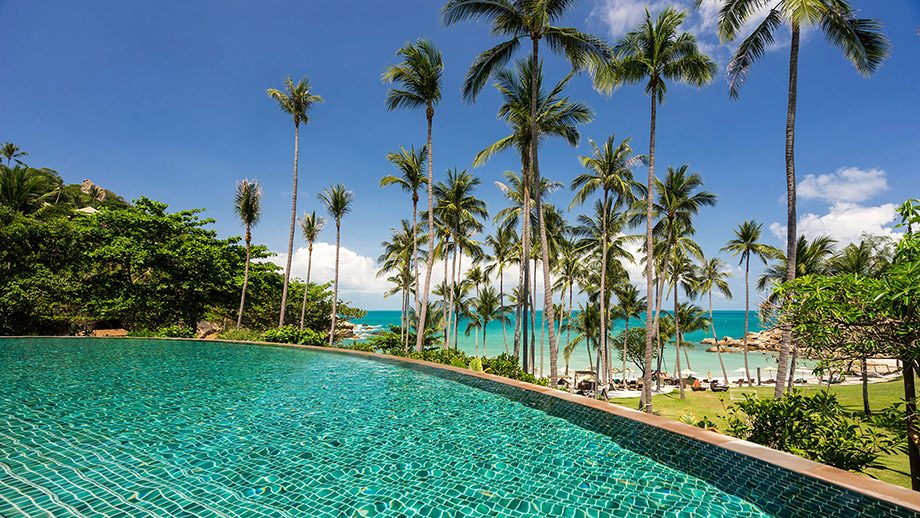 Main pool framed by palms above the beach at Banyan Tree Samui