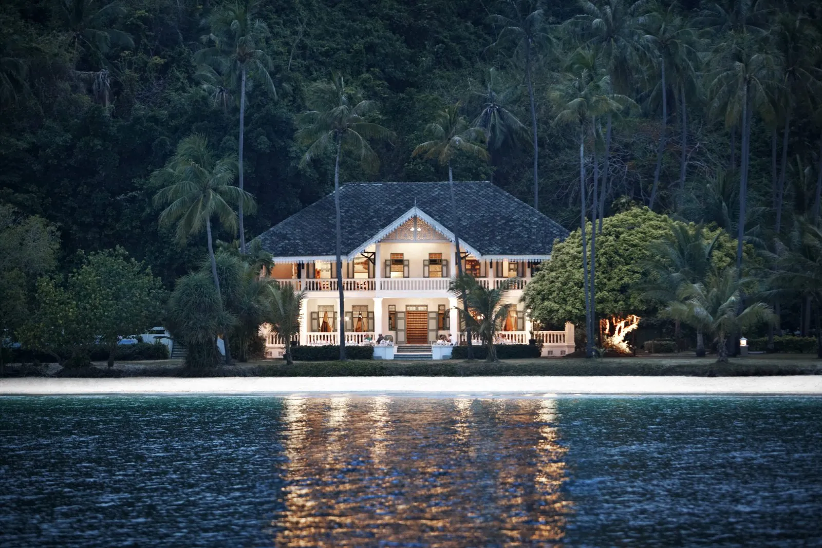 Panwa House Thai restaurant lit up at night by the water at Cape Panwa Hotel, Phuket