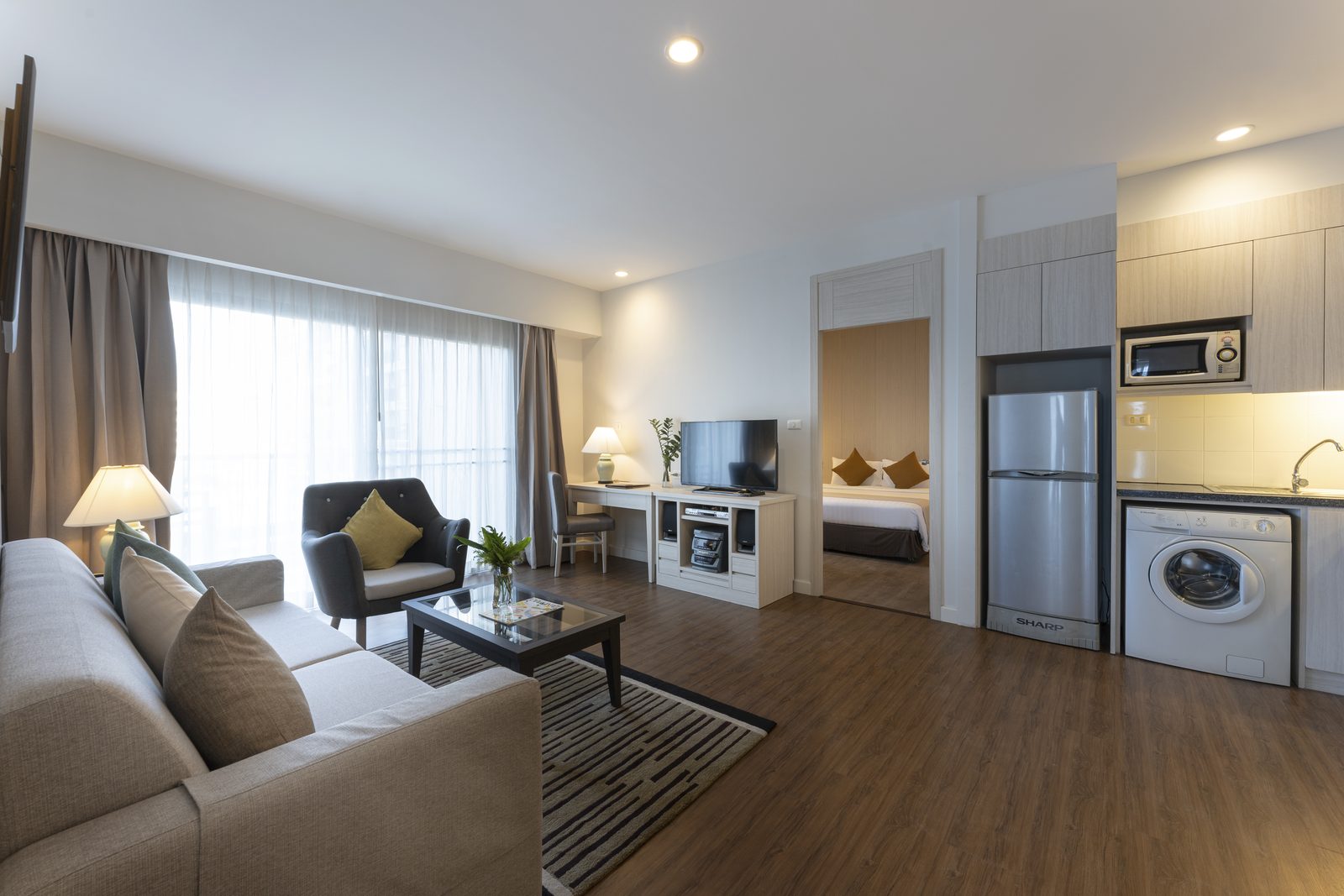 Deluxe Two Bedroom Suite living area with kitchen and washing machine at Cape Racha Hotel, Sriracha