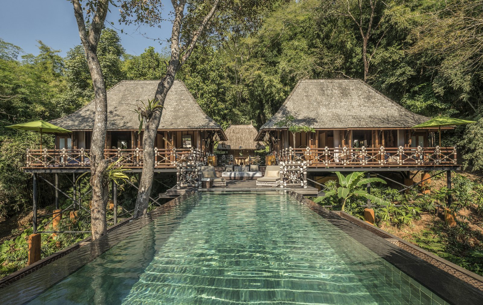 Pool below thatched pavilions in the jungle at Four Seasons Tented Camp Golden Triangle