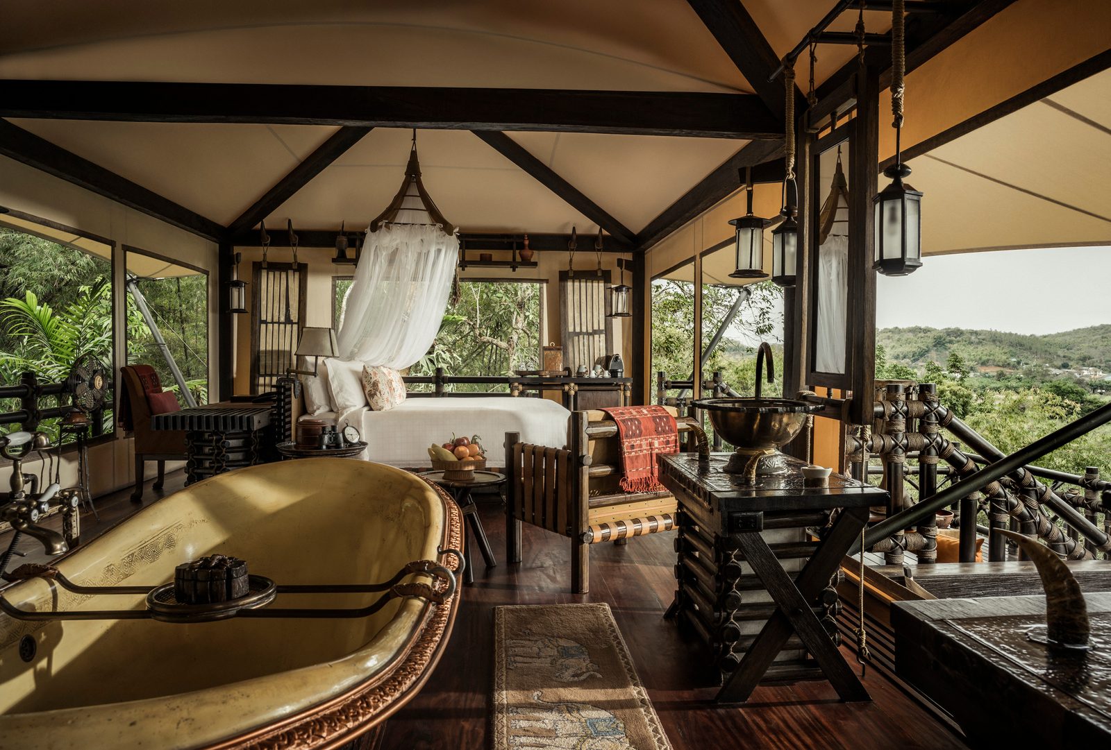Tent interior with a four-poster bed and a hammered copper bathtub at Four Seasons Tented Camp Golden Triangle
