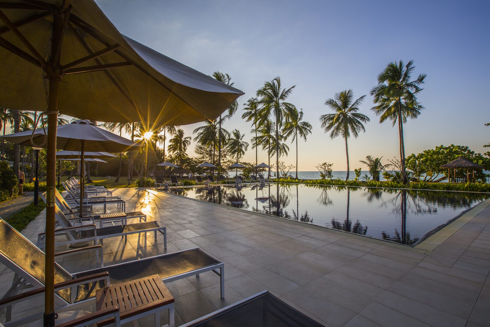 Ocean Pool with loungers and palms at sunset at Kantary Beach Hotel, Khao Lak