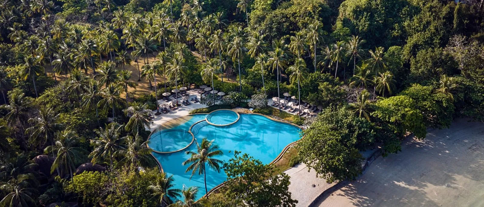 Aerial view of the free-form swimming pool among coconut palms at Rayavadee, Krabi