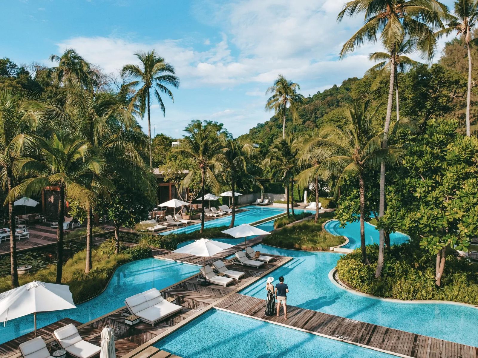 Free-form pool among palms at Rosewood Phuket, beside Emerald Bay