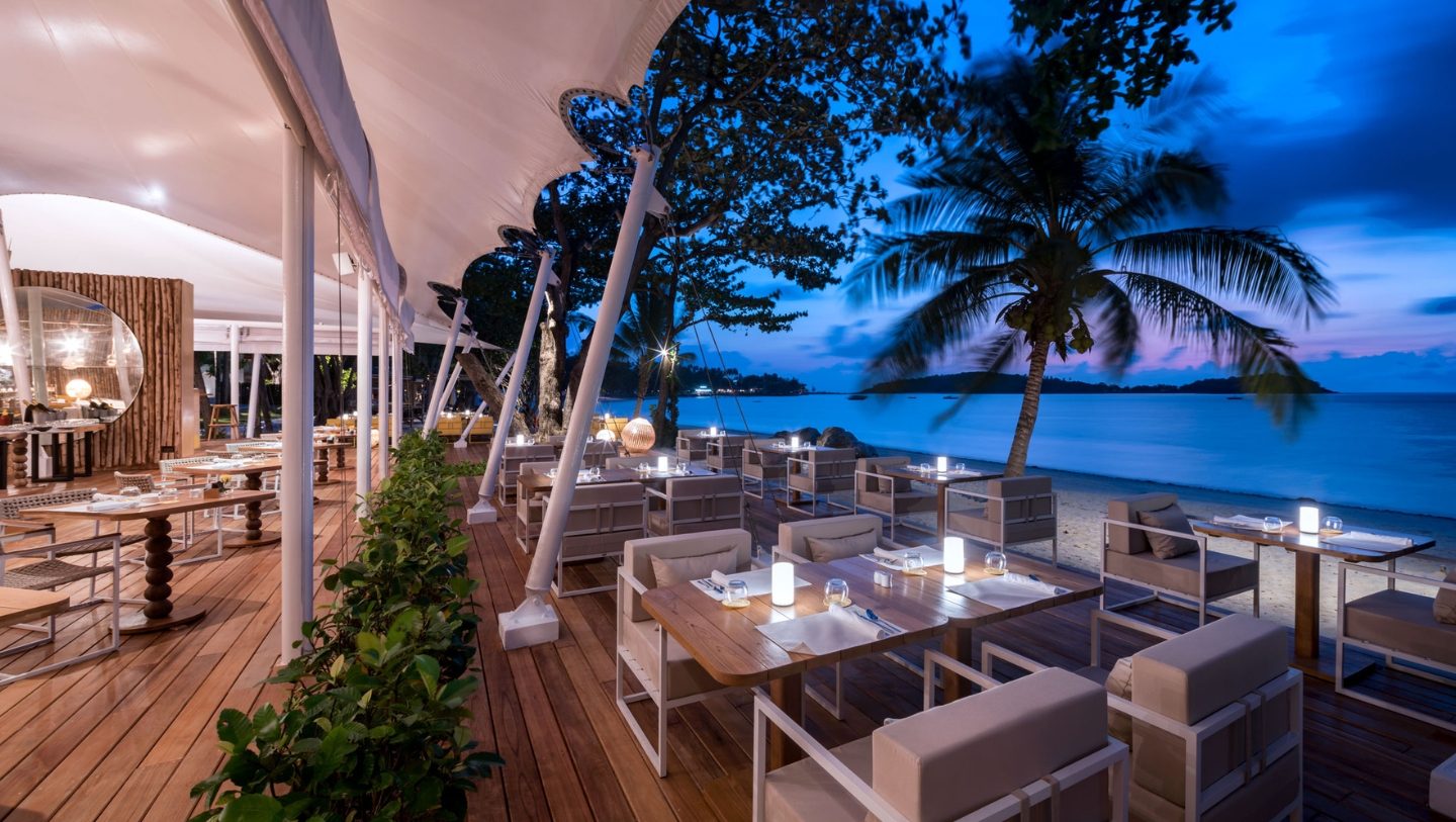 Beachfront restaurant deck at dusk overlooking Chaweng Beach at SALA Samui Chaweng Beach Resort