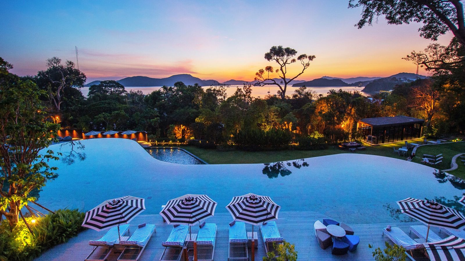 Pool with sun loungers at The Habita, Sri Panwa Phuket, at dusk