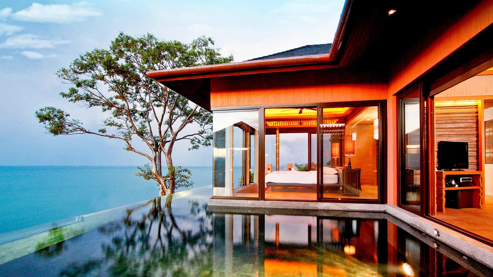 Pool villa at Sri Panwa Phuket with an infinity-edge pool around a glass-walled bedroom