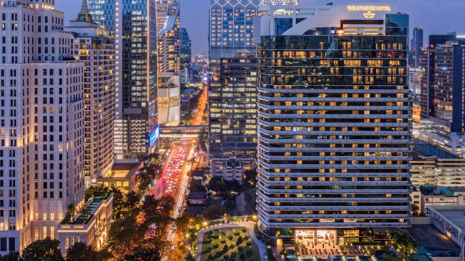 The Athenee Hotel tower on Wireless Road, Bangkok, at dusk with the city skyline behind