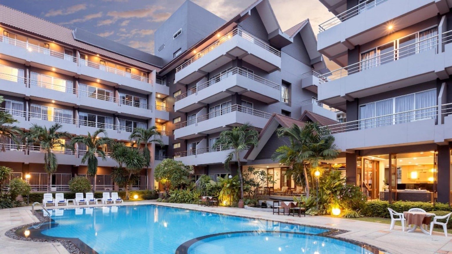 Hotel buildings and outdoor swimming pool at dusk at The Holiday Resort Pattaya