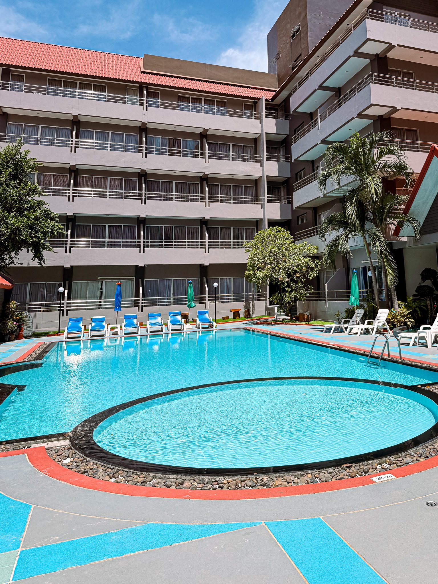 Outdoor swimming pool courtyard by day at The Holiday Resort Pattaya