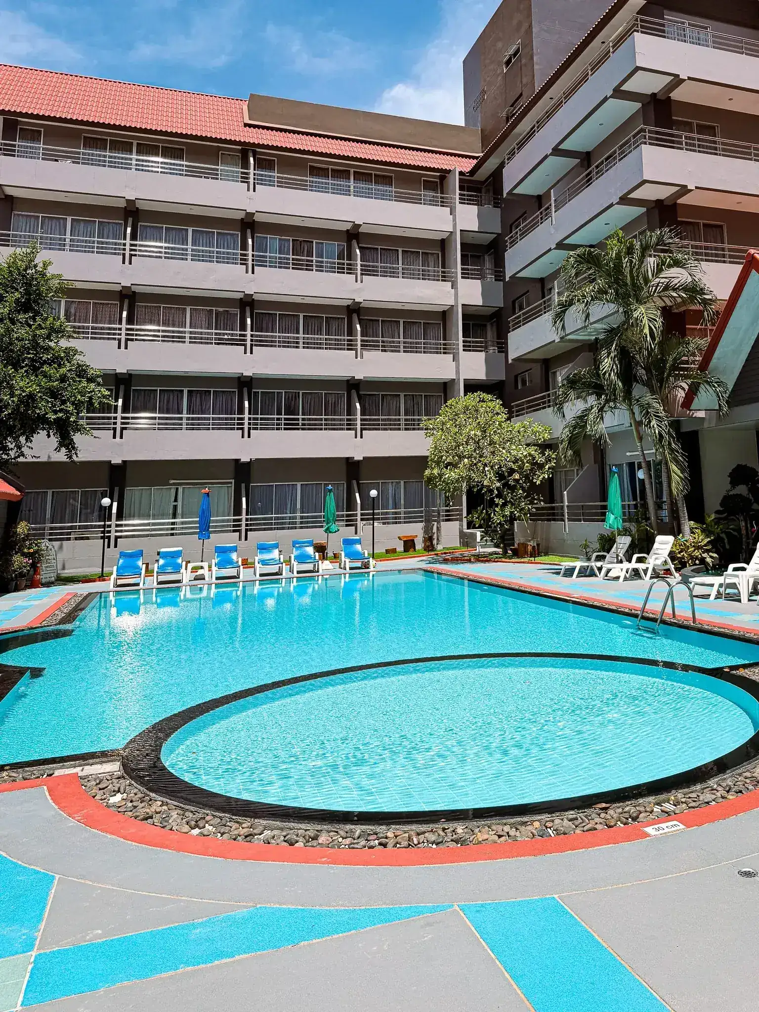 Outdoor swimming pool courtyard by day at The Holiday Resort Pattaya