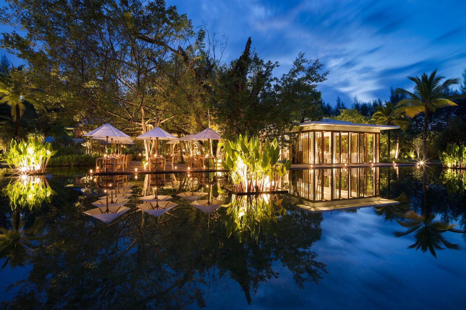 Ficus restaurant at The Sarojin lit at night and reflected in the pond