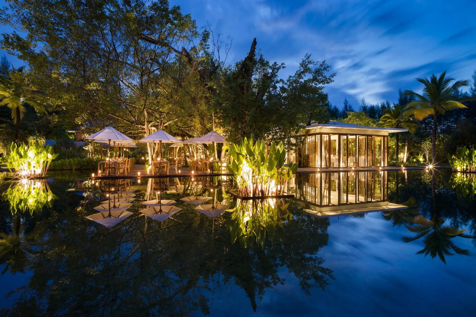 Ficus restaurant at The Sarojin lit at night and reflected in the pond