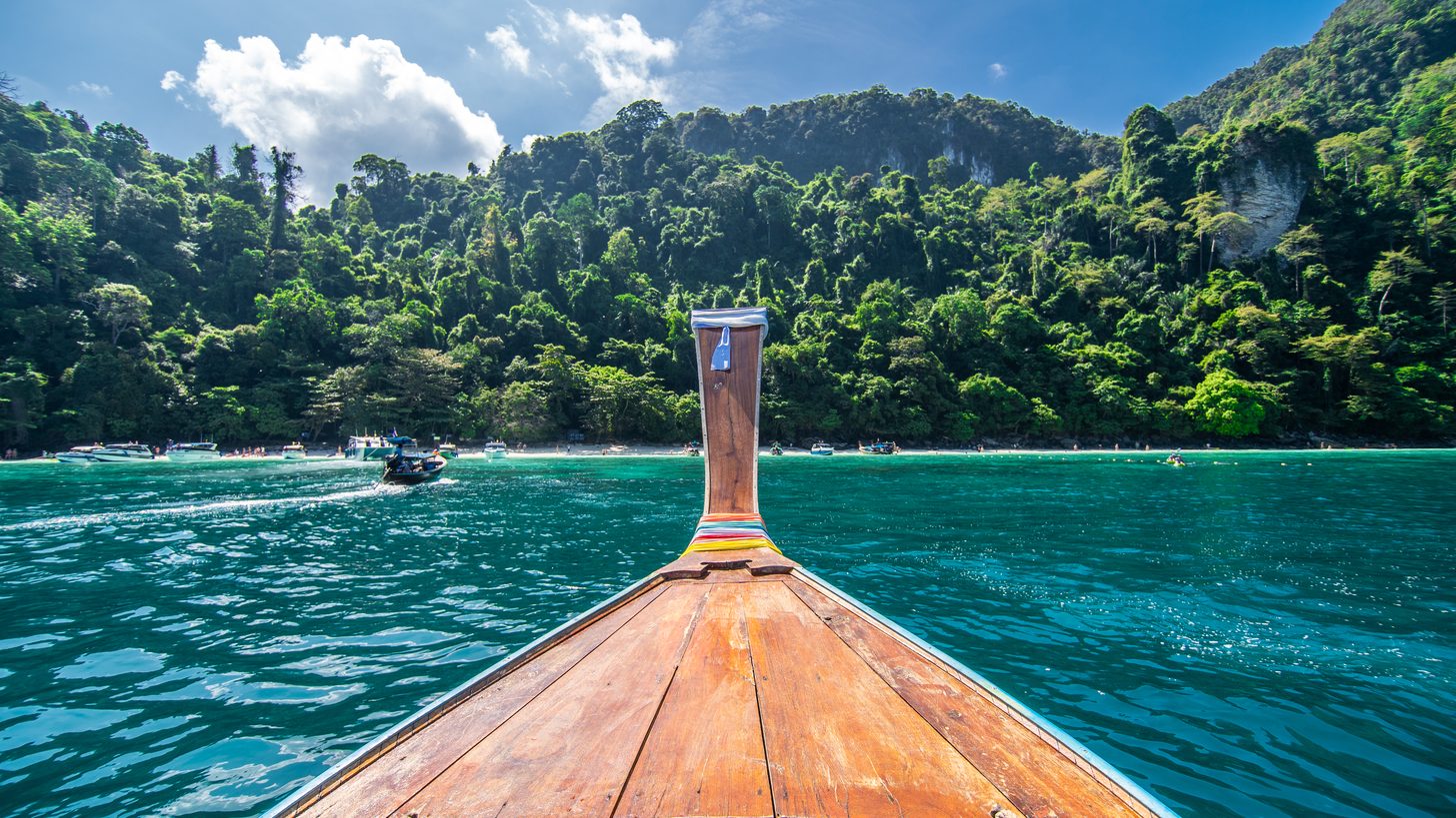 Longtail boat on turquoise water beneath the limestone karsts of Maya Bay, Krabi, Thailand