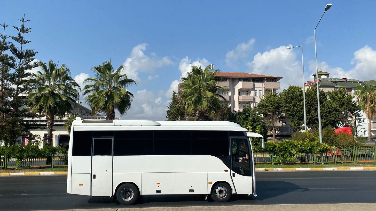 Modern coach on a palm-lined road in Thailand — Explera managed transport fleet