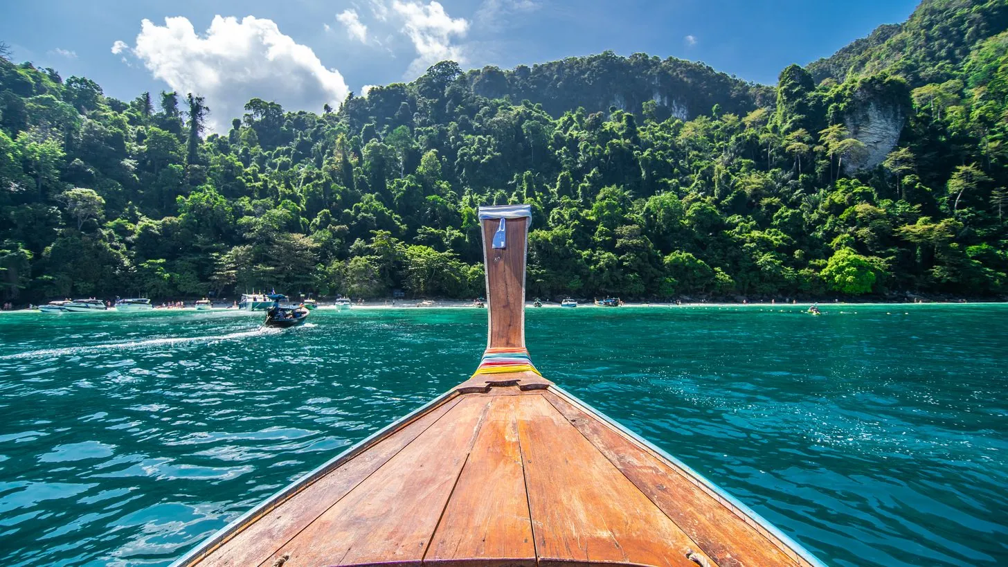 Longtail boat in the turquoise water of Maya Bay — the classic Thailand itinerary image travel agents sell