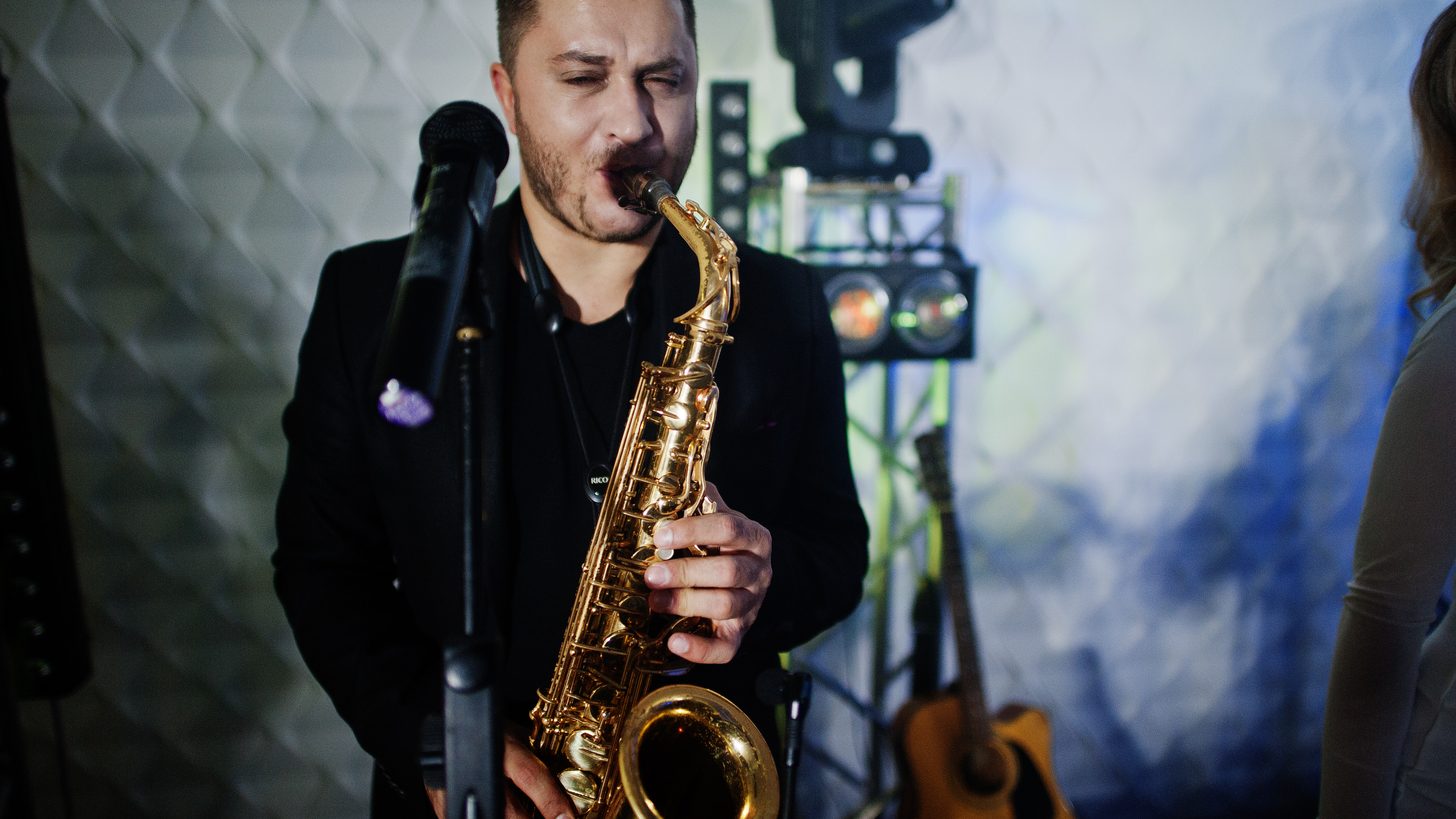 A live band with saxophone performing under stage lights
